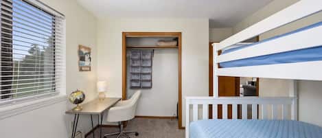 Un dormitorio con literas, un escritorio, una silla, un globo terráqueo y un armario.