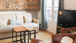 Ein Wohnzimmer mit einer Couch, einem Couchtisch, einem Fernseher und einem großen Wandbild.
