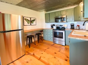 Functional kitchen with refrigerator, microwave, and oven, perfect for preparing meals.
