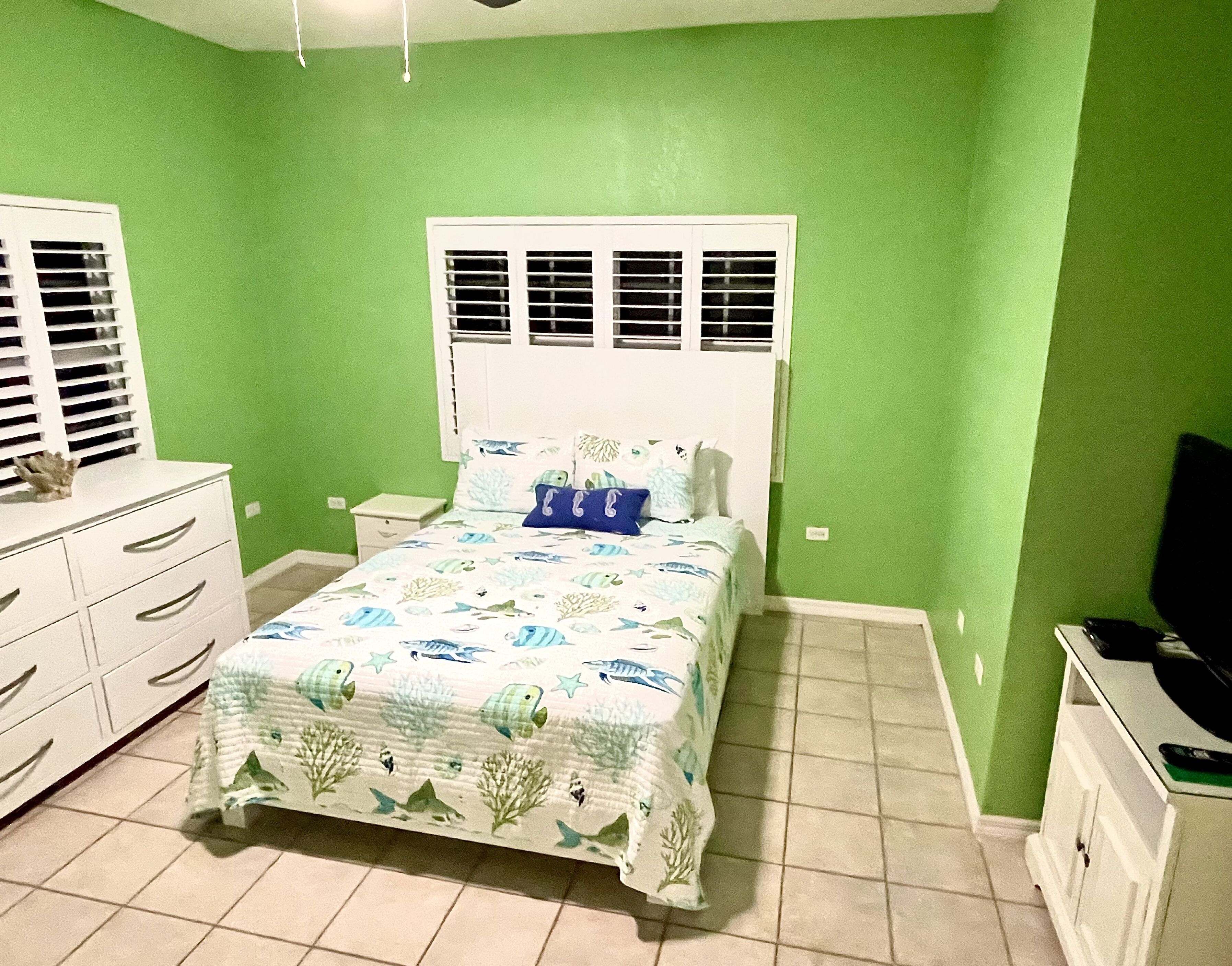 Une chambre à coucher comprenant un lit, des tables de chevet, une commode et un téléviseur.