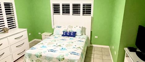 Une chambre à coucher comprenant un lit, des tables de chevet, une commode et un téléviseur.