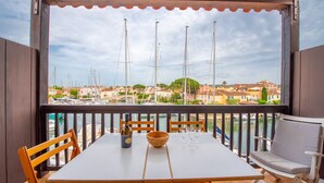 Un balcon avec une table, des chaises et une vue sur les bateaux et les bâtiments.