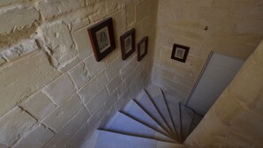 Una escalera de caracol con paredes de piedra y cuadros enmarcados.