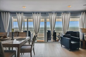 Ein Balkon mit Meerblick, ausgestattet mit einem Tisch, Stühlen und einer Couch.