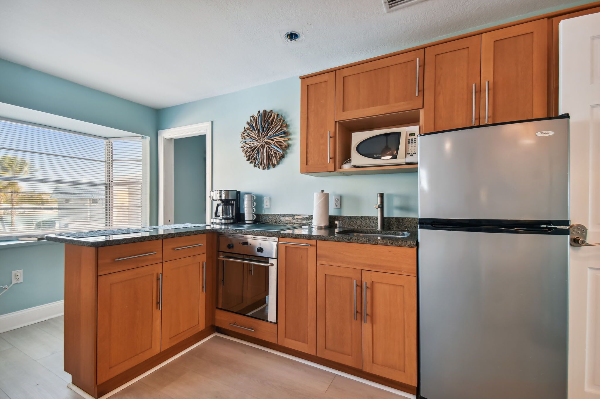 A kitchen with wooden cabinets, a stainless steel refrigerator, a microwave, and a built-in oven.