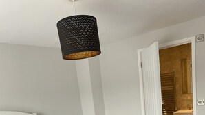 Une chambre à coucher avec un lit, une lampe suspendue et une porte ouverte donnant sur une salle de bain.