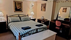 Une chambre bien rangée, avec un lit, des tables de chevet, une chaise et une commode.