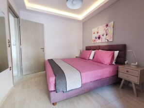 A modern bedroom with a bed, nightstands, and a ceiling light fixture. - Mon Repo Nest (Corfu)