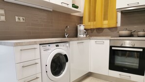 A modern kitchen with a built-in washing machine, oven, and coffee maker. - Mon Repo Nest (Corfu)