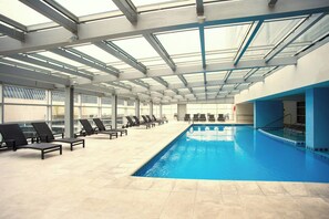 Una piscina cubierta, una piscina al aire libre, tumbonas
