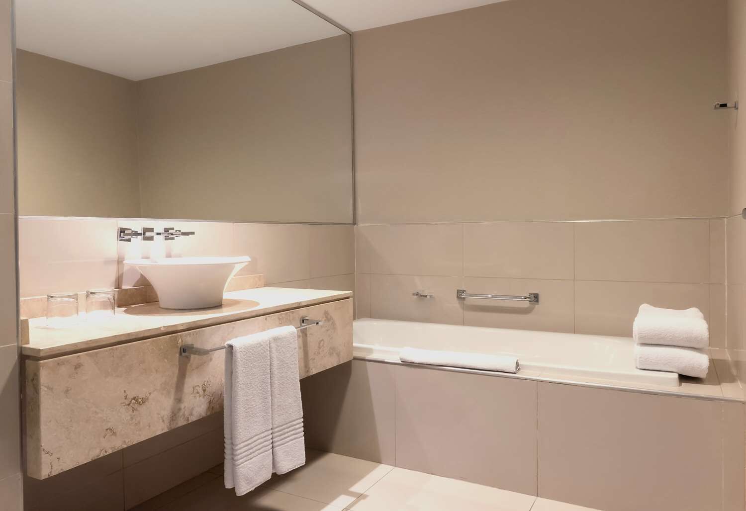 Ein modernes Badezimmer mit einem großen Spiegel, einem Waschbecken und einer Badewanne.