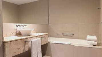 Ein modernes Badezimmer mit einem großen Spiegel, einem Waschbecken und einer Badewanne.
