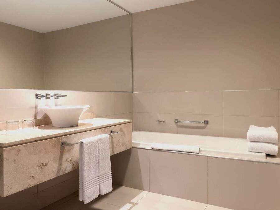 Ein modernes Badezimmer mit einem großen Spiegel, einem Waschbecken und einer Badewanne.