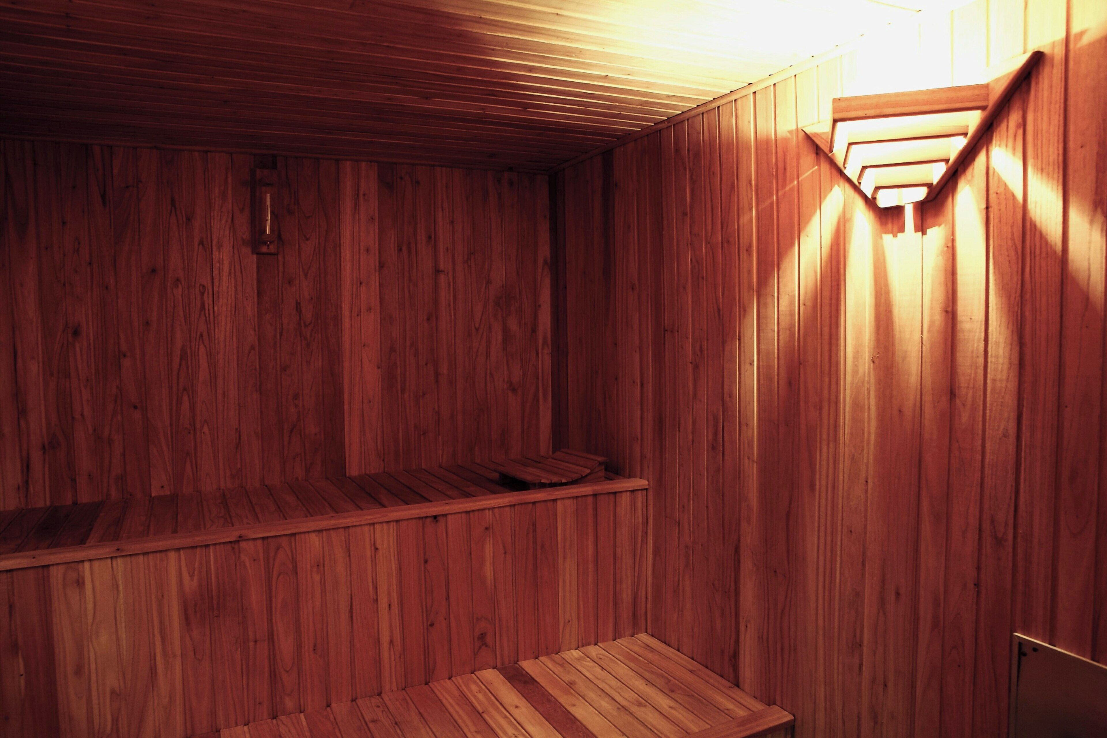 A wooden sauna with a bench and a sloped ceiling.