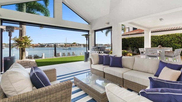 A modern outdoor living area with a view of the marina, a grill, and comfortable seating.