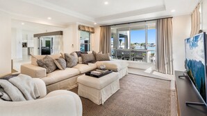 A modern living room with a beige sofa set, a patterned rug, and a large TV.