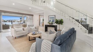 A spacious living area with a modern staircase, a fireplace, and a view of the marina.