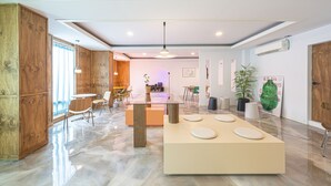 A modern interior with a wooden accent wall, a central table with chairs, and a large potted plant. - The Shourin in Daejeon (Daejeon)