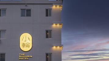 Ein Hotelgebäude mit einem Schild, auf dem 'The Shorin Hotel' steht, und einer großen, beleuchteten Beschilderung mit chinesischen Schriftzeichen.