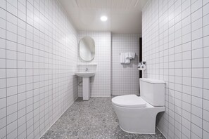 A small, modern bathroom with white tiles, a pedestal sink, a toilet, and a mirror. - The Shourin in Daejeon (Daejeon)