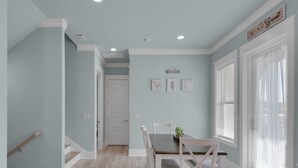 Un espace repas comprenant une table et des chaises, un escalier et un couloir menant à une autre pièce.