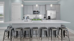 Une cuisine moderne dotée d’un grand îlot central, d’appareils électroménagers en acier inoxydable et de tabourets de bar.