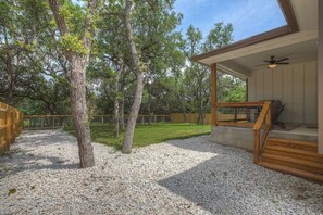 Un espacio al aire libre techado con un piso de madera, un ventilador de techo y suelo de grava.