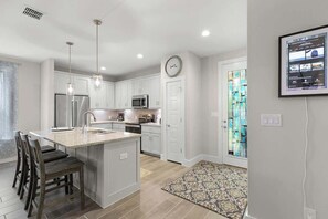 Una cocina moderna con armarios blancos, electrodomésticos de acero inoxidable e iluminación colgante.