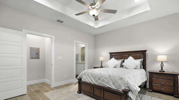 A bedroom with a bed, bedside tables, a ceiling fan, and a door.