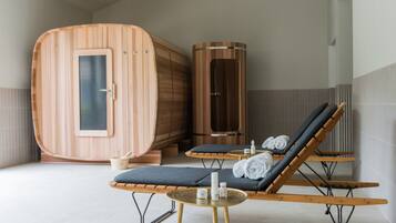 Uma área de spa moderna com saunas de madeira, cadeiras relaxantes e uma pequena mesa com toalhas e garrafas.