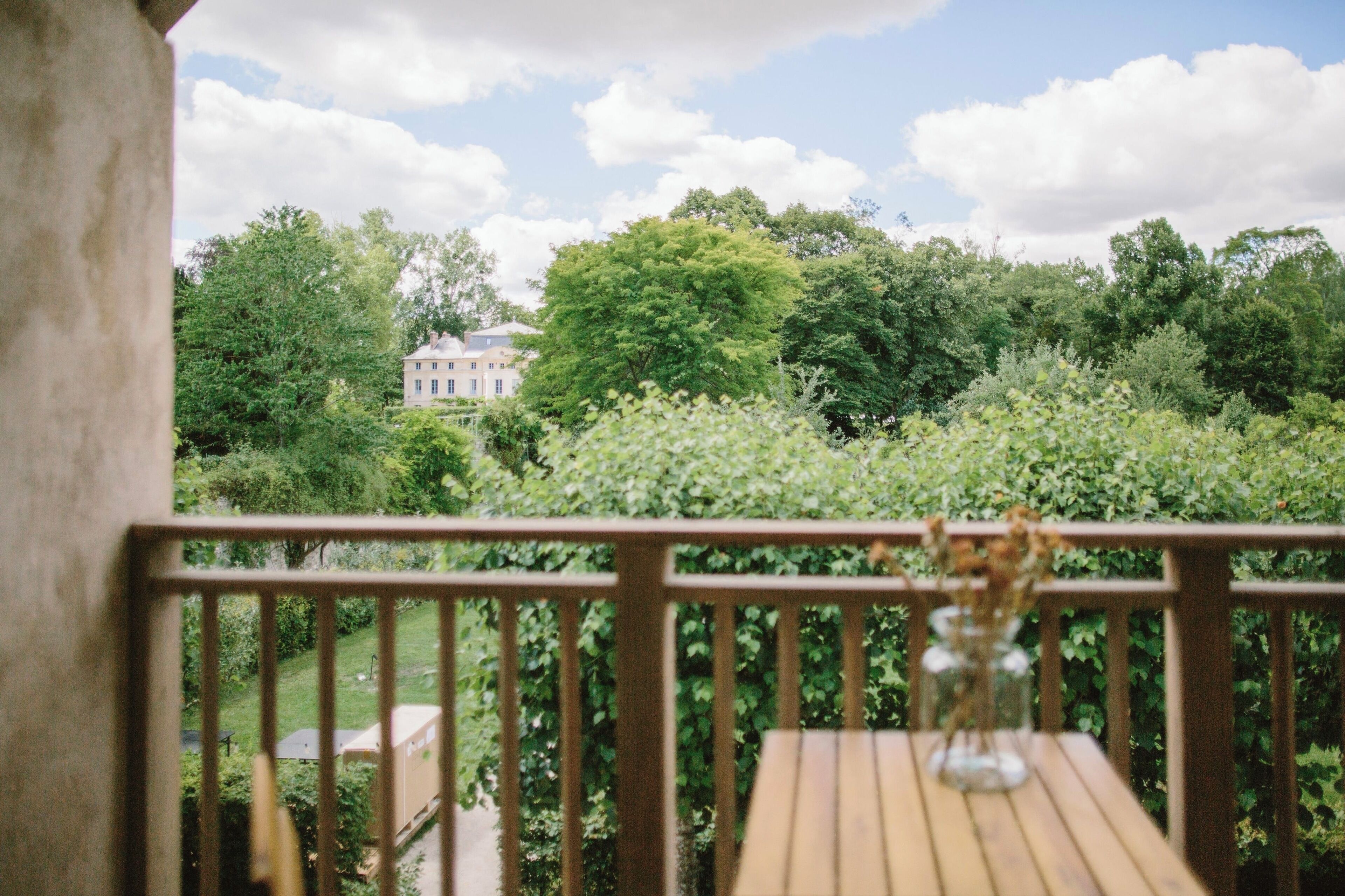 Une terrasse en bois offrant une vue sur un jardin luxuriant et un bâtiment situé au loin.
