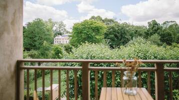 Une terrasse en bois offrant une vue sur un jardin luxuriant et un bâtiment situé au loin.