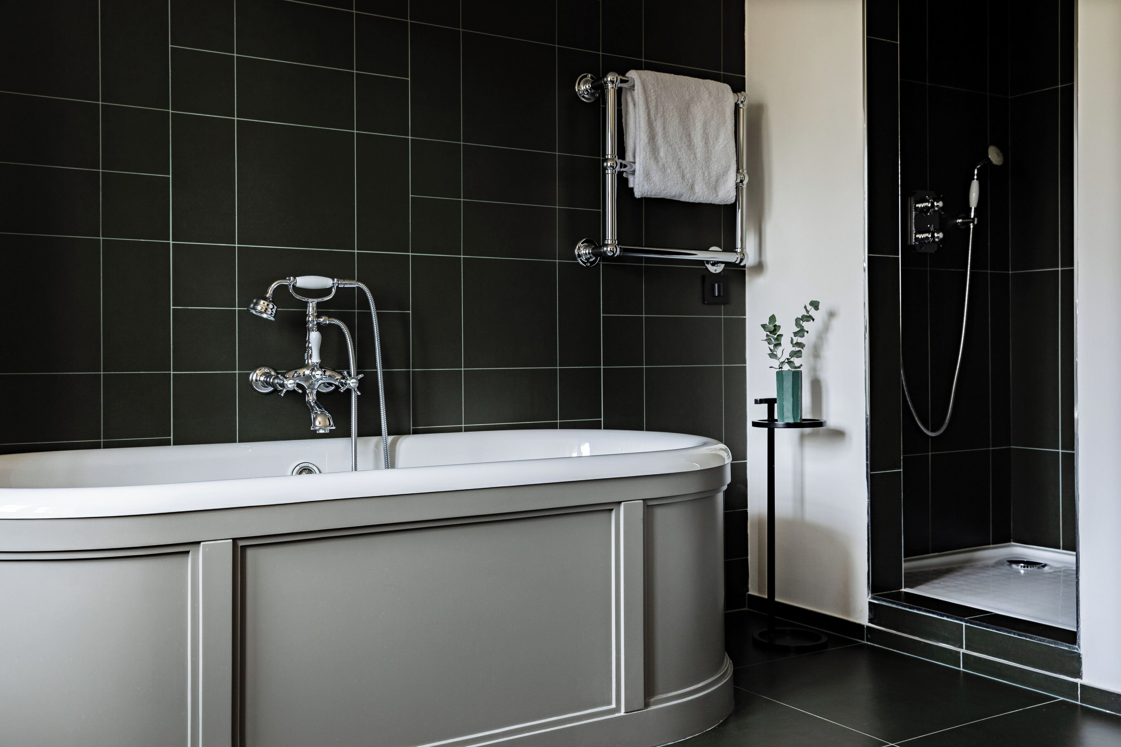 Un baño moderno con una bañera independiente, ducha y perchero para toallas.