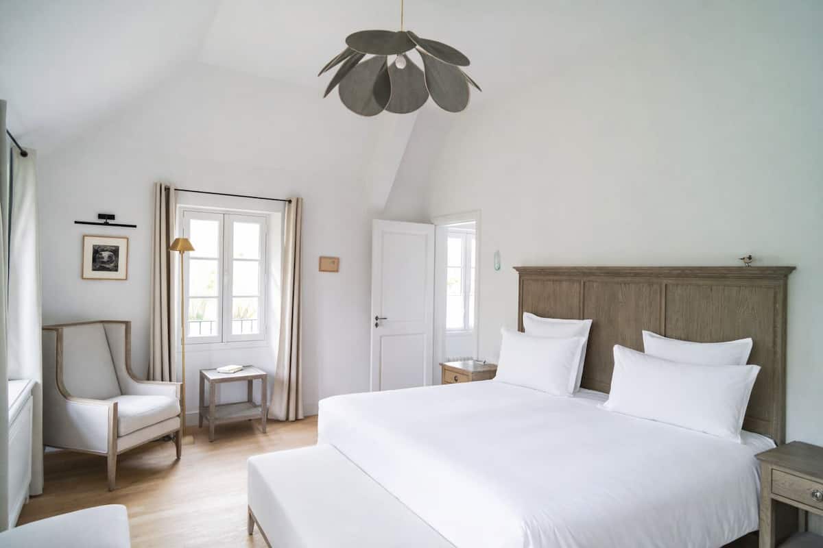 A bedroom with a large bed, a wooden headboard, a desk, and a chair.