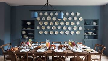 A dining room with a table set for breakfast, surrounded by chairs, with a wall of plates above.