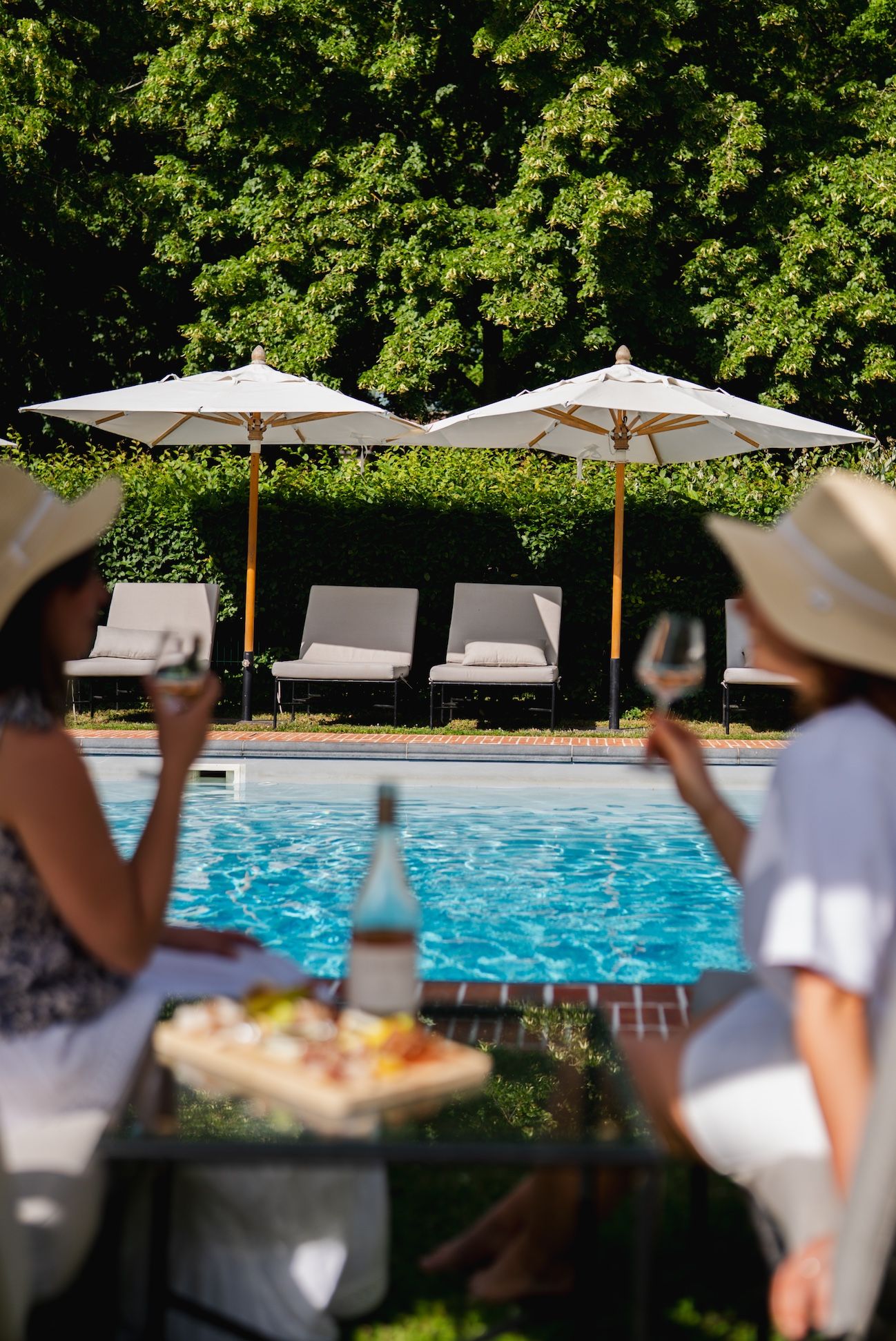 A poolside setting with lounge chairs and umbrellas, a dining table with food, and a clear view of the pool.