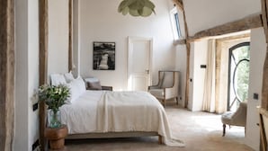 Un dormitorio con cama, una silla, un escritorio, una ventana y una puerta.