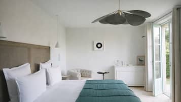 A bedroom with a large bed, a bedside table, a chair, and a view of the outdoors through a door.
