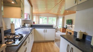 Une cuisine moderne équipée d’une cuisinière à gaz, d’un plancher en bois et d’un coin repas avec une table et des chaises.