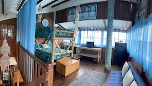 Um quarto com uma cama de solteiro e beliche, uma escrivaninha e um sofá.