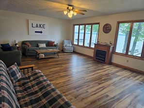 A living room with a fireplace, a couch, a coffee table, and a sign pointing to the lake.
