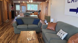 A living room with a sofa, coffee table, and a kitchen in the background.