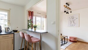 Eine moderne Küche mit Barbereich, einem Esstisch mit Stühlen und einem großen Fenster mit Vorhängen.
