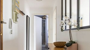 Ein Flur mit Holzboden, einem Tisch mit Korb und Pflanze sowie einem Spiegel an der Wand.