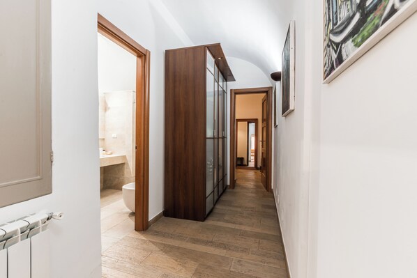 A hallway with a wooden cabinet, a radiator, and a framed artwork on the wall.