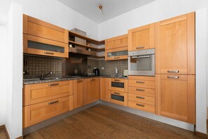 Una cucina con pensili e basi in legno, forno integrato e microonde.