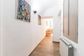 Un corridoio con pavimento in legno, pareti bianche e opere d'arte.