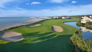 Ein Golfplatz mit Bunkern, einem Wasserabschnitt und Strandimmobilien.
