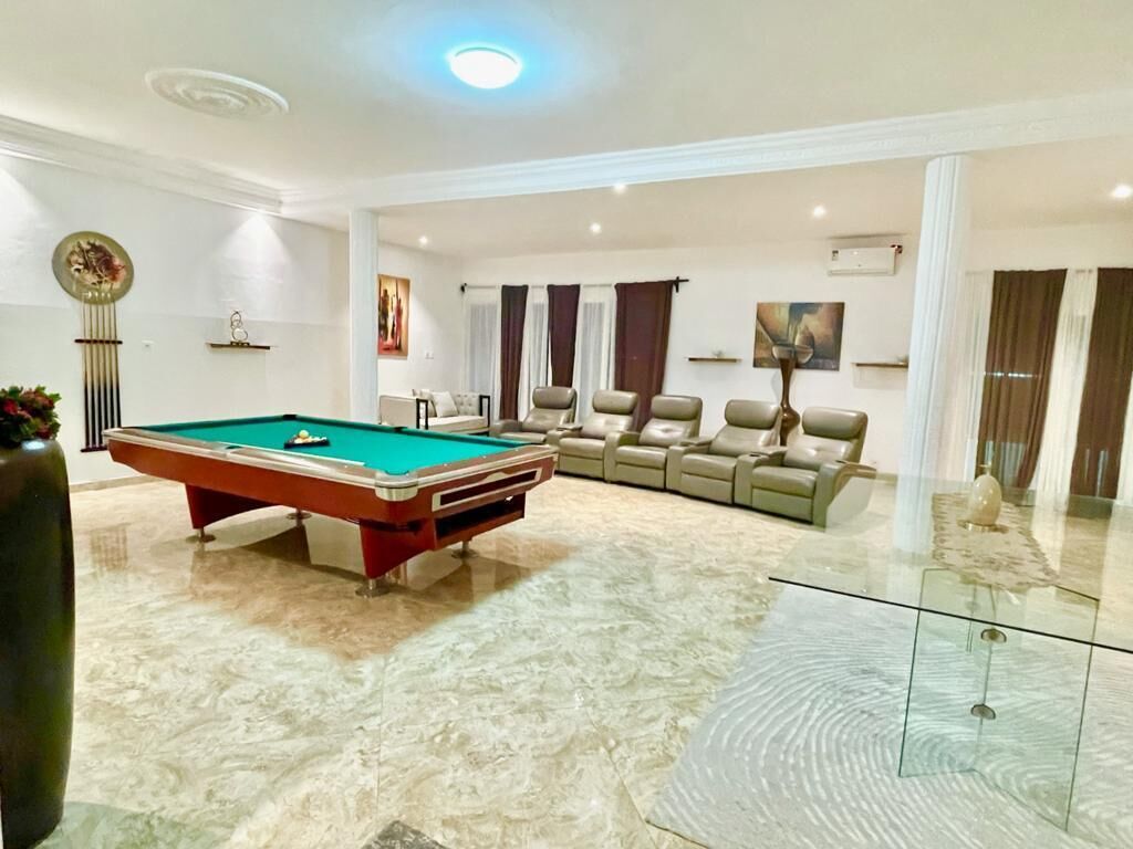 Un amplio salón con mesa de billar, asientos cómodos y una mesa de centro de vidrio.