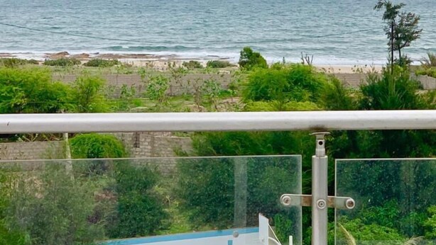 A view of a beach with the ocean in the background, a clear sky, and some greenery in the foreground. -  Villa Yenne Dakar Diamniadio (Sendou)